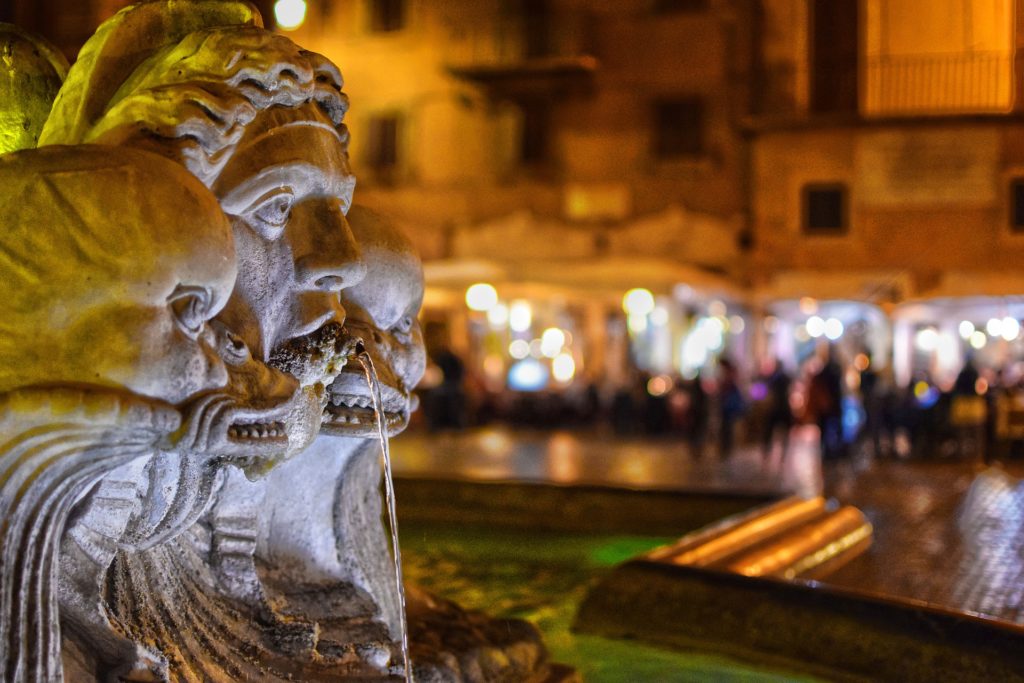 Jedna z římských fontán ve večerním světle, v pozadí náměstí Piazza Navona.