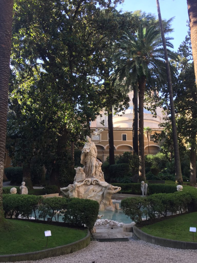 Malá zahrada uvnitř paláce - "giardino interno" s malým jezírkem se sousoším, s palmami a krátce střiženým trávníkem.