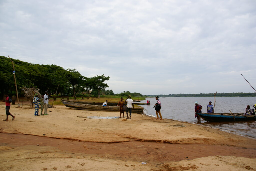 Pláž v místní vesnici s lesem v okolí a několika loďkami.