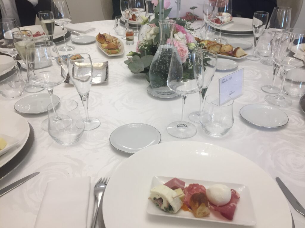 Svátečně nazdobený svatební stůl s květinami, laděnými do růžova.