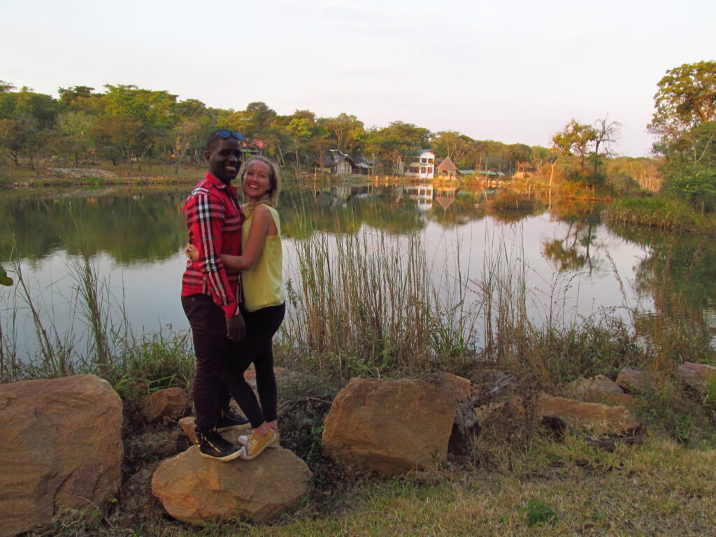 Zuzana a Chris, stojící na kameni, v pozadí jezero nebo rybník.